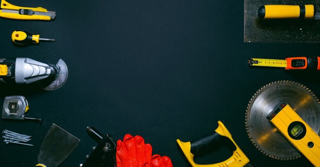 Flat lay of various construction tools on black background, perfect for ads with copy space.