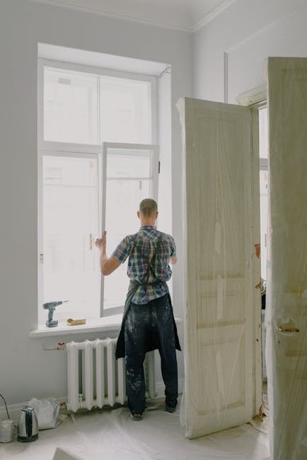pexels-photo-5691551-5691551 Full-length view of a handyman fixing a modern window in a bright room.